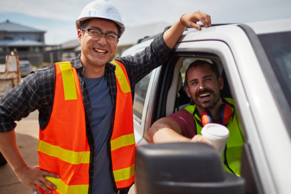 Worker smiling by colleague sitting in car at site