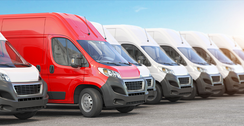 Red delivery van in a row of white vans. 
